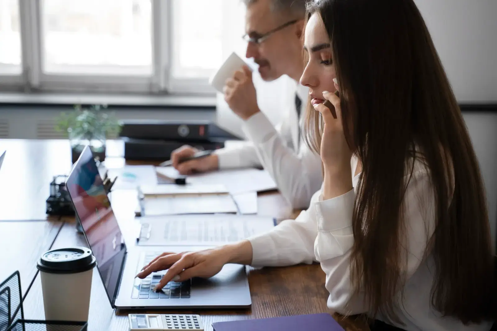 Profesionales de Datatech trabajando con un portátil e informes de proyecto en la oficina