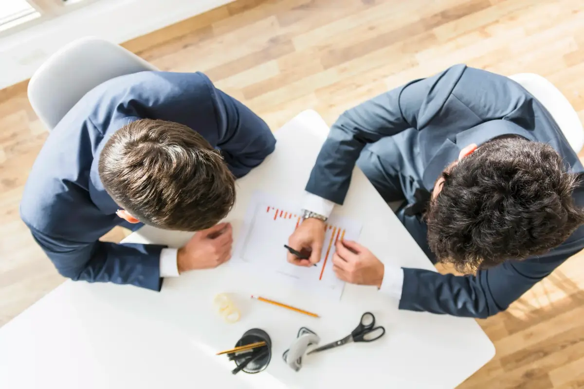 Dos consultores revisando un informe financiero sobre una mesa, vistos desde arriba