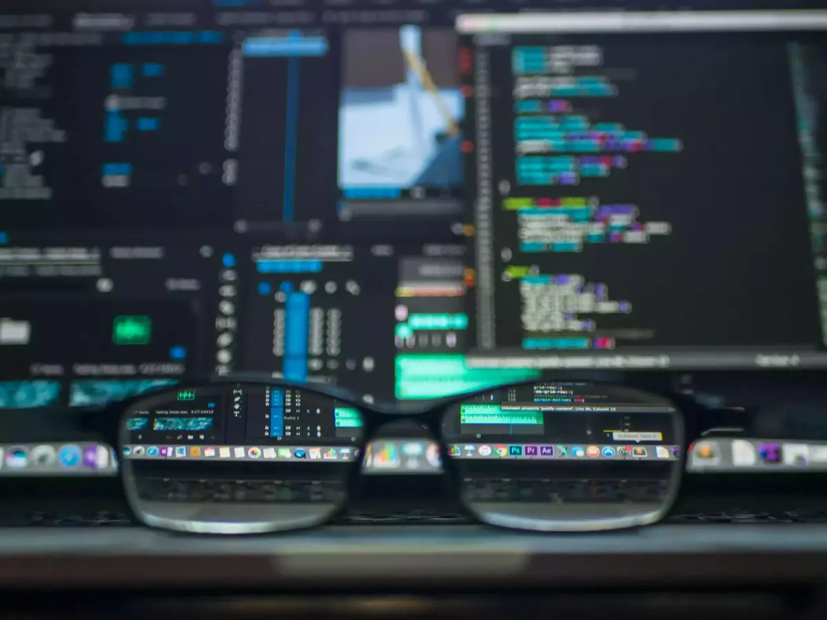 Pantallas con código de pruebas de software y unas gafas en primer plano